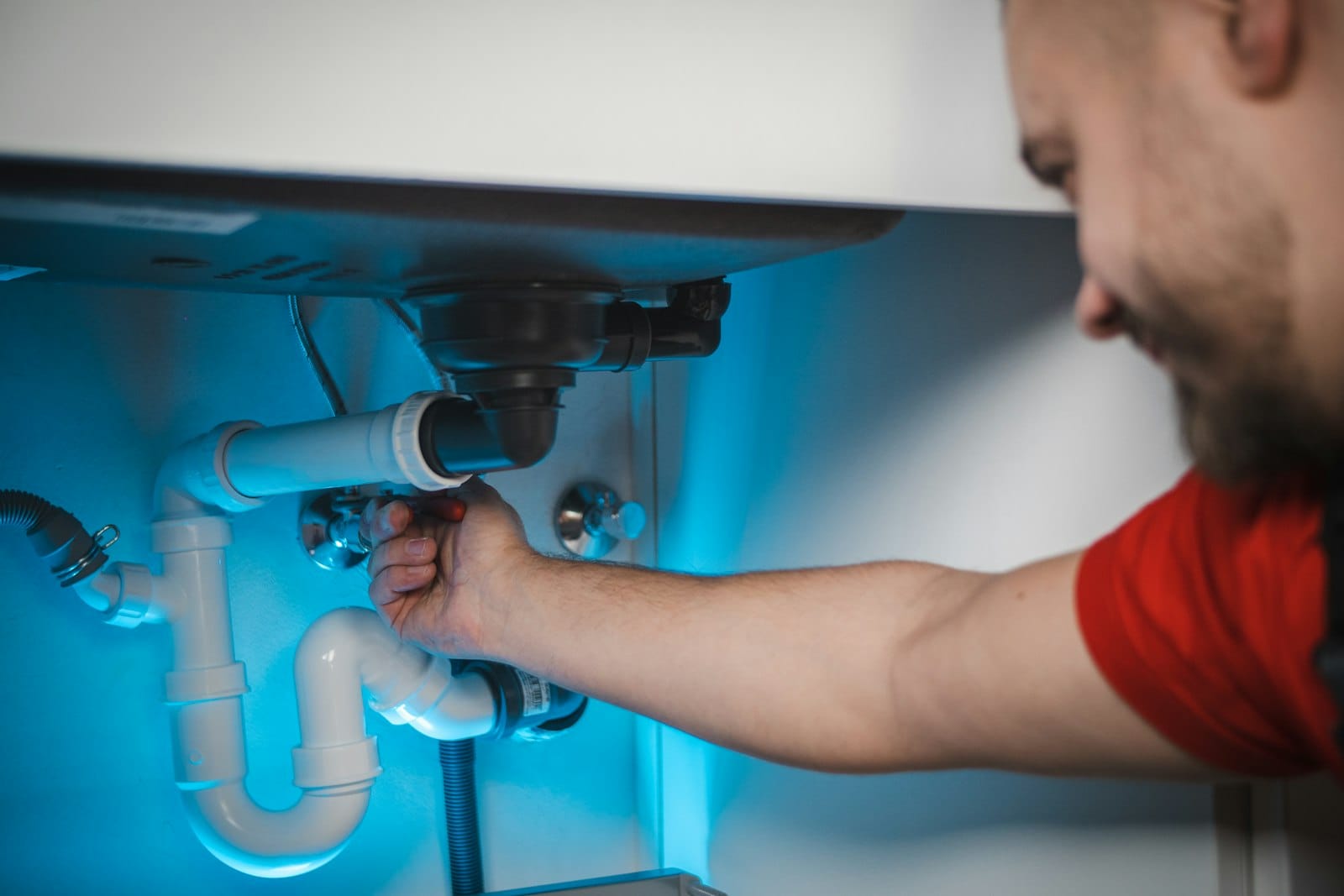 Plumber at work under a sink